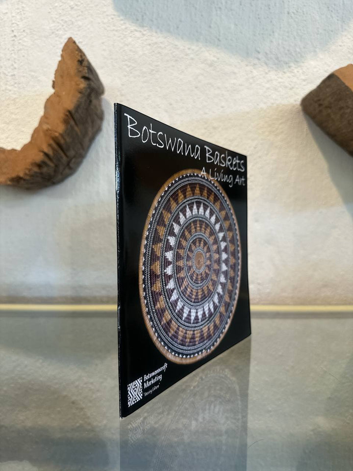 Book with a circular design and text 'Botswana Baskets Living Art' on a textured surface.