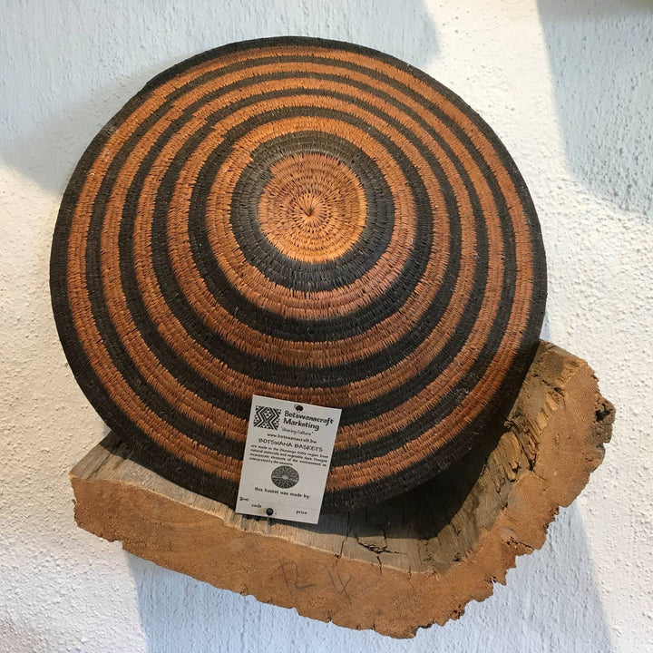 Wooden coaster with concentric circle pattern on a wooden block against a white wall