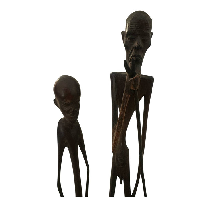 Two wooden sculptures of humanoid figures on a white background