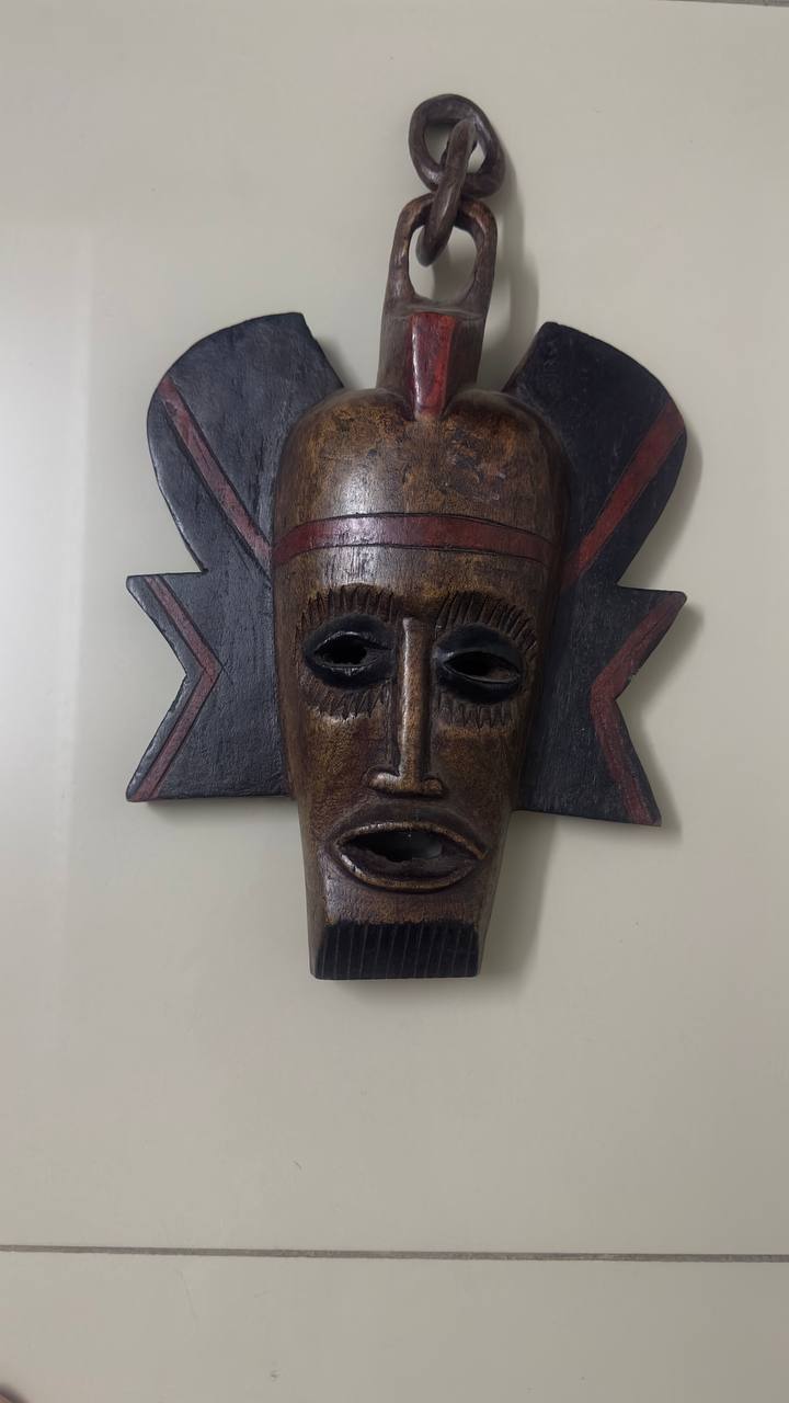 Wooden mask with decorative elements on a plain background