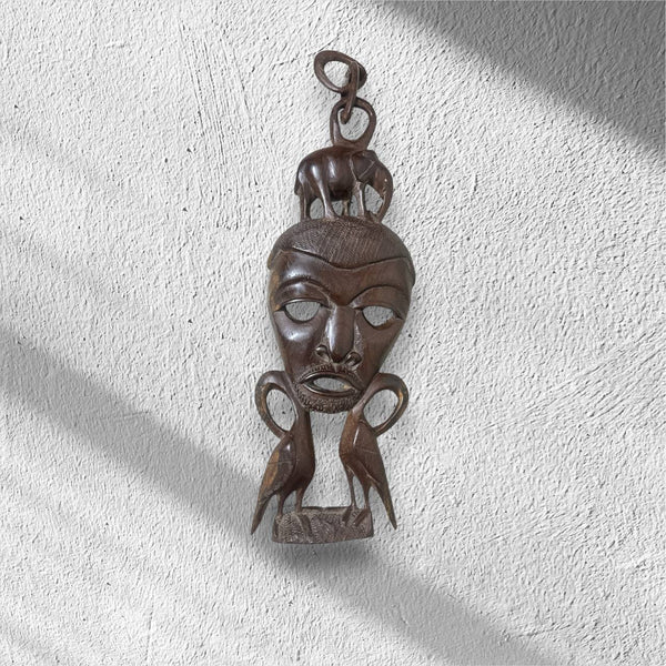 Decorative wooden mask hanging on a textured white wall