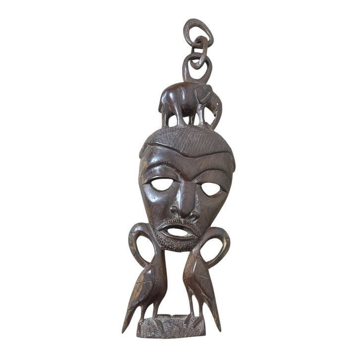Decorative wooden mask hanging on a textured white wall