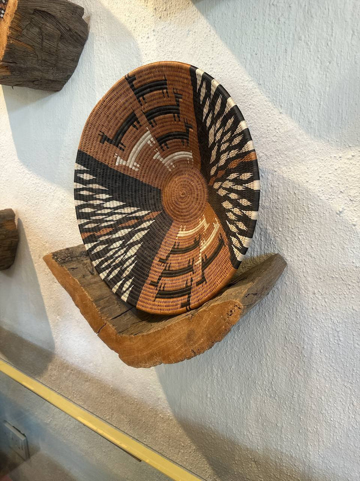 Decorative woven basket with geometric patterns on a textured wall.