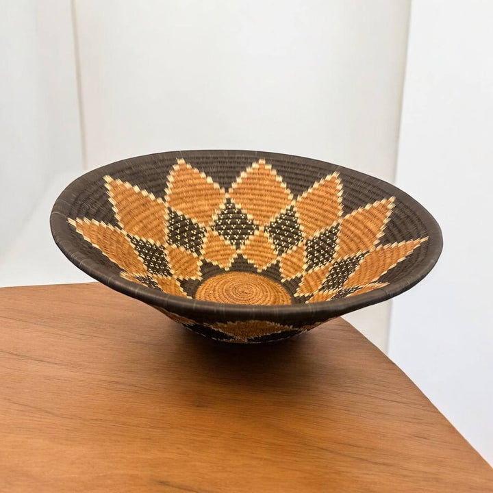 Decorative woven bowl with geometric pattern on a wooden surface
