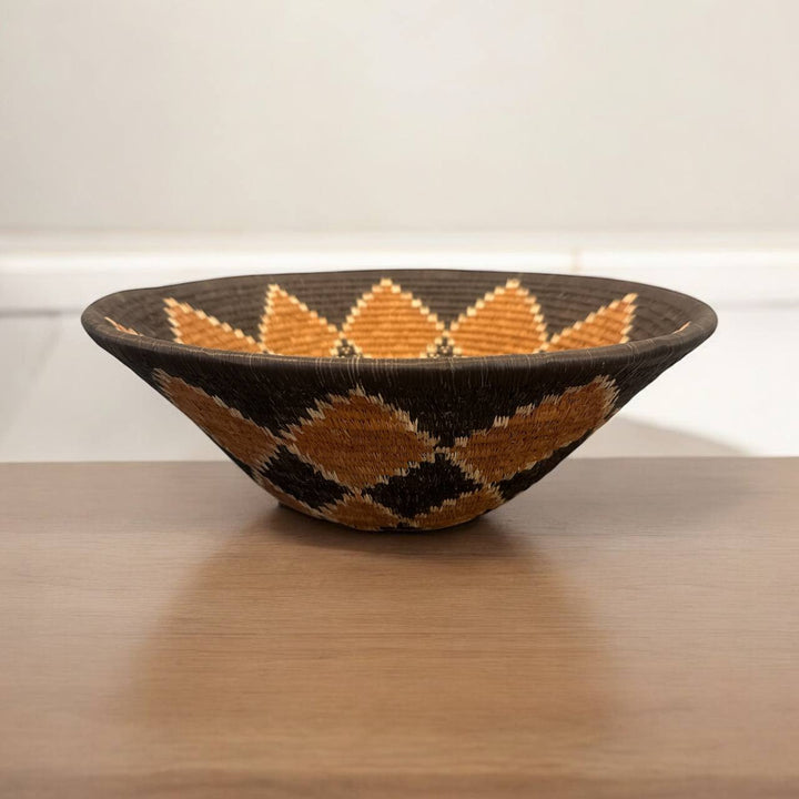 Woven bowl with geometric pattern on a wooden surface