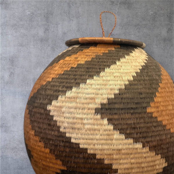 Woven spherical woven basket with geometric pattern on a gray background