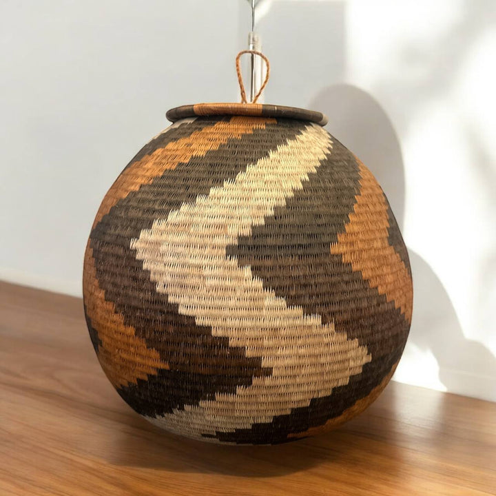 Woven spherical woven basket with geometric pattern on a gray background