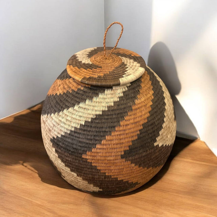 Woven spherical woven basket with geometric pattern on a gray background