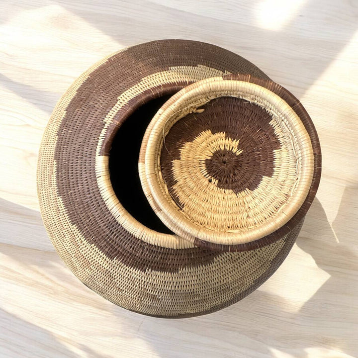 Two woven baskets with brown and beige pattern on a light wooden surface