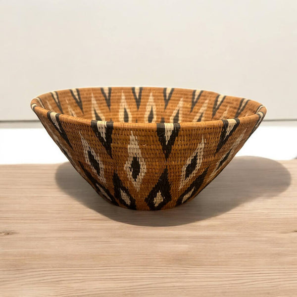 Woven basket with a geometric pattern on a wooden surface