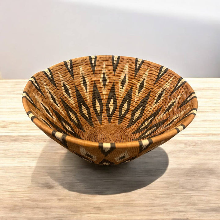 Woven basket with a tiger stripe pattern on a wooden surface