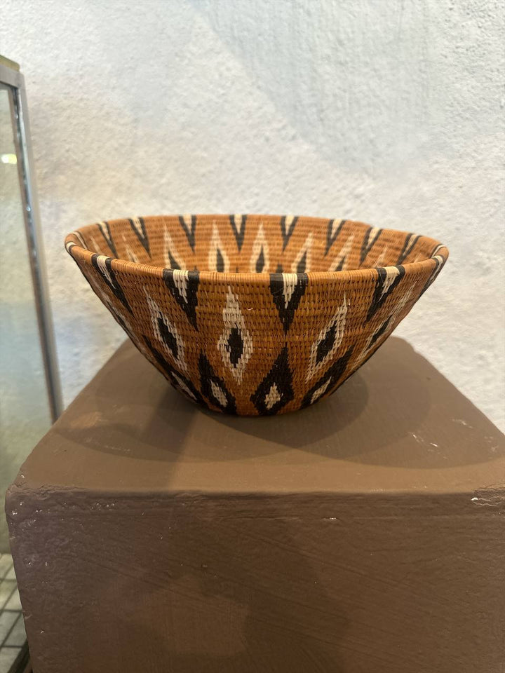 Woven basket with geometric pattern on a textured surface