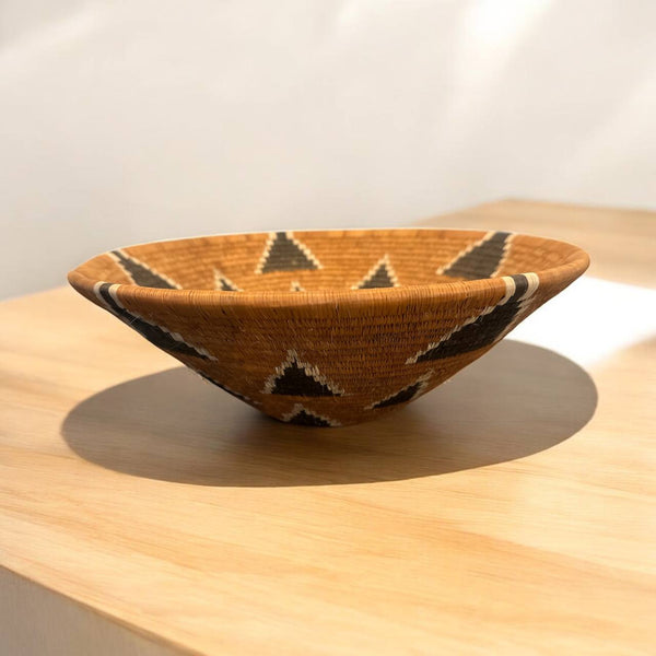 Woven bowl with geometric pattern on a wooden surface