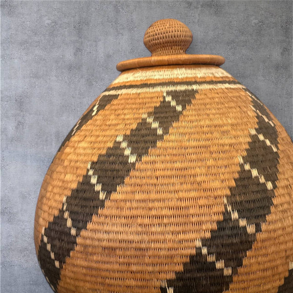 Woven basket with a lid featuring geometric pattern on a gray background