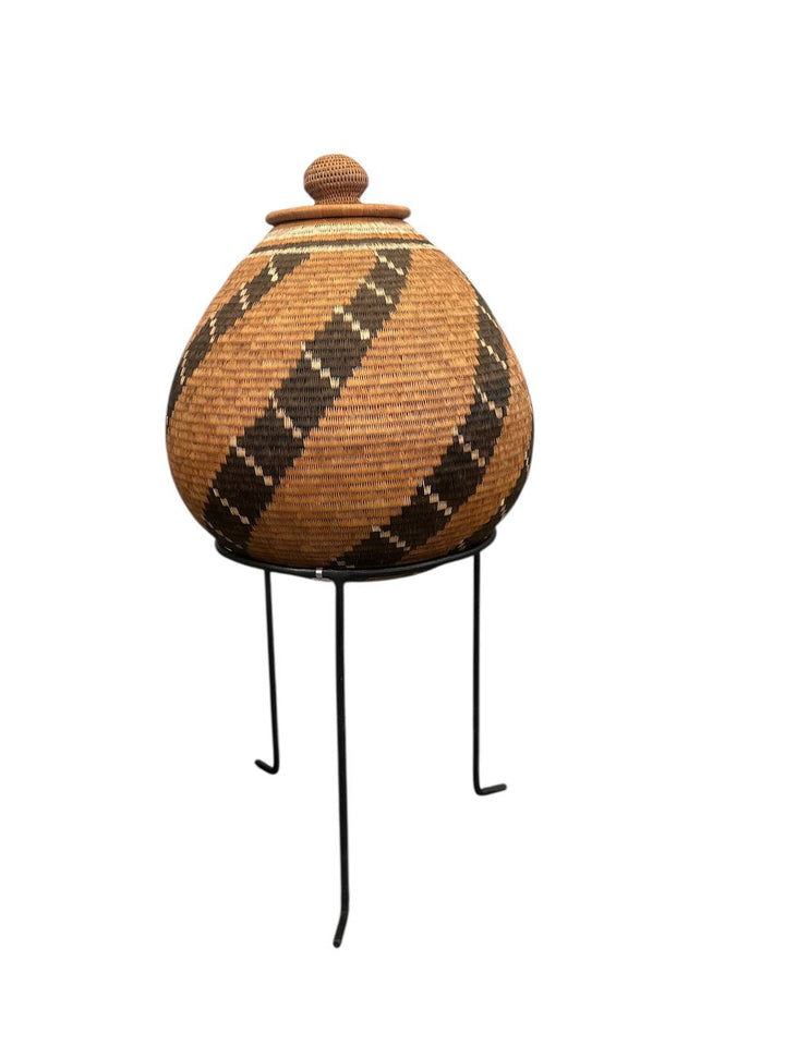 Woven basket with a lid on metal stands against a white background