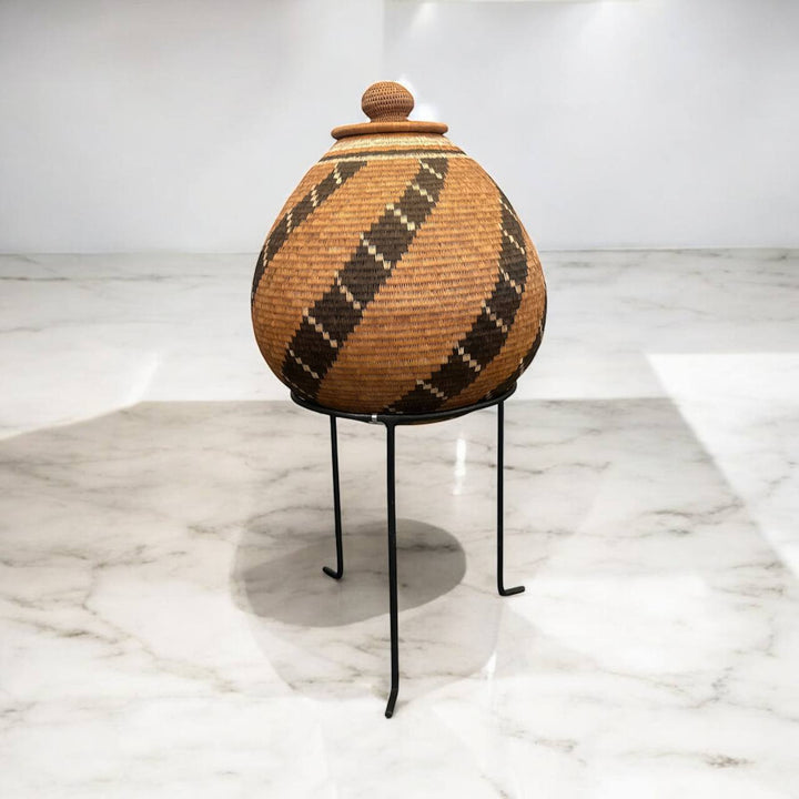 Woven basket with lid on a stand against a white background