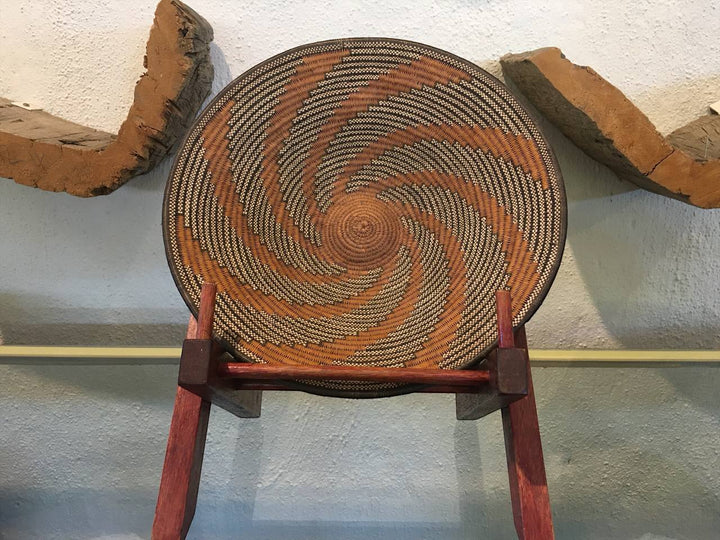 Woven basket on a wooden stand against a textured wall.